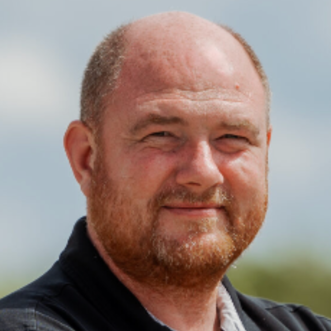 Portræt af Paw, indehaver af JAC Kloakteknik, iført sort polo og med blå himmel i baggrunden.